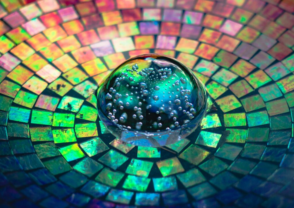 Colorful mosaic pattern with a glass bubble sphere reflecting vibrant rainbow colors.